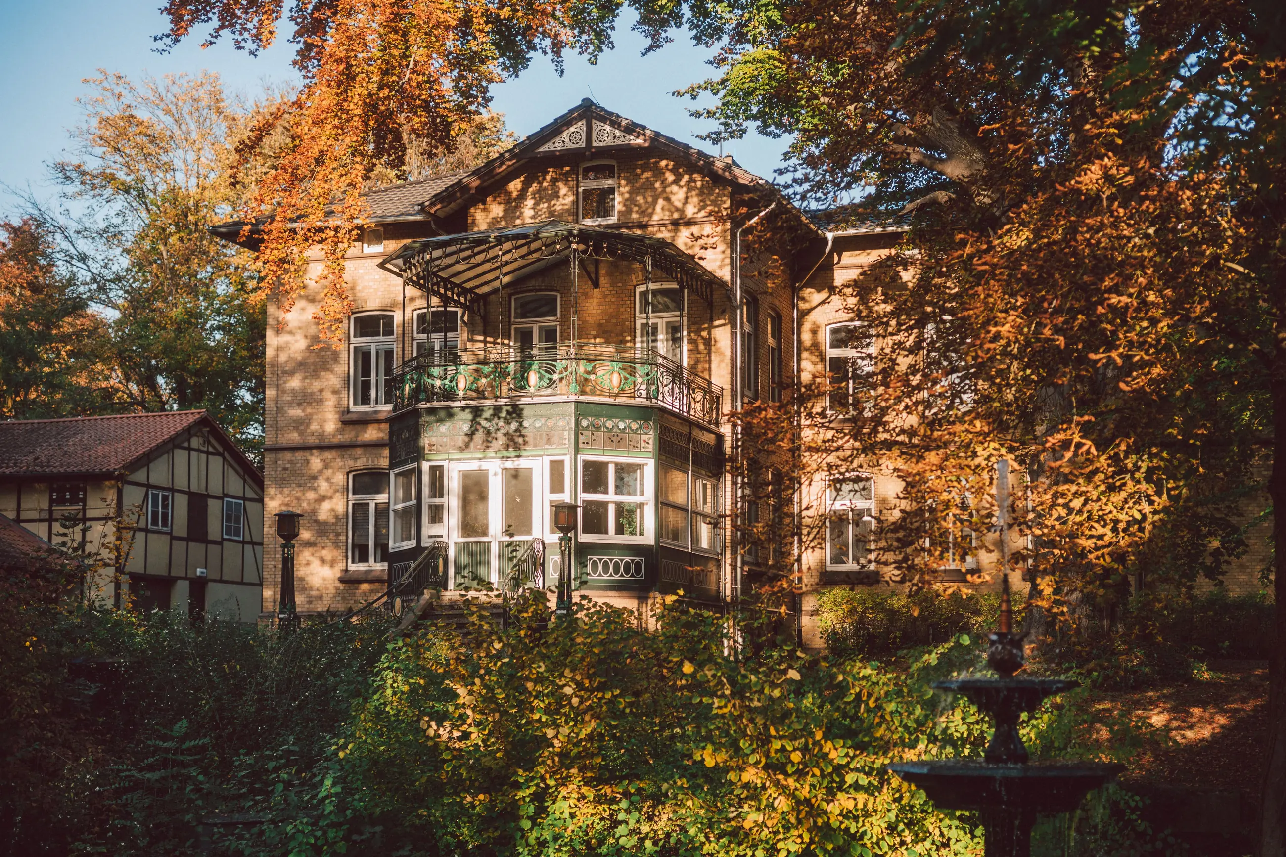 Gründerzeitvilla mit gusseiserner Veranda und Wintergarten in einem herbstlichen Garten