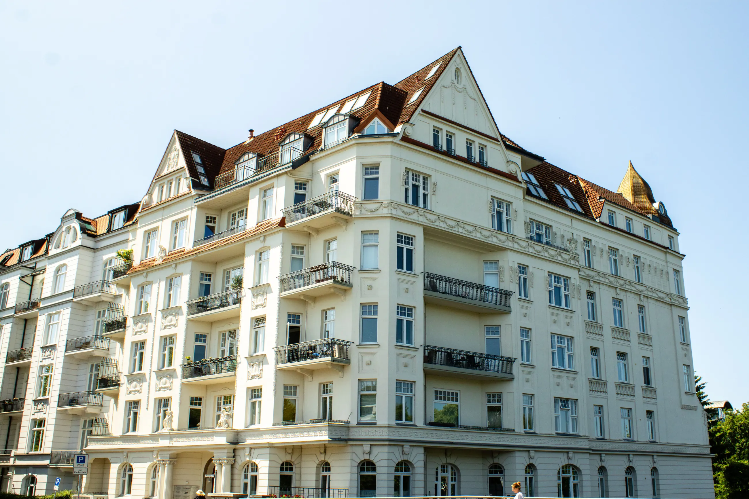 Jugendstil-Mehrfamilienhaus mit Balkonen und Erkern unter blauem Himmel